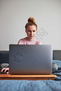 室内的青少年在COVID19隔离在线课程教中在家电脑上远程用笔记本电脑做功课学习坐在电脑前看屏幕的远程女孩学习如何在电脑面前看着图片