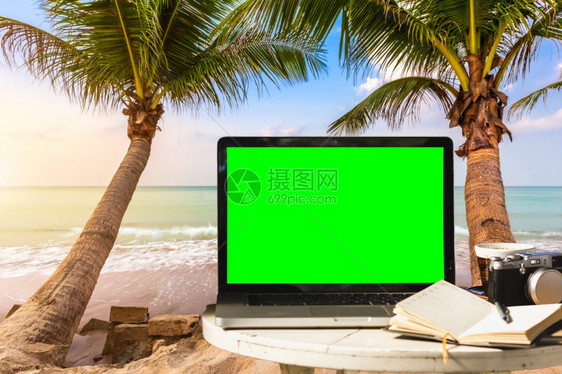 杯子监视器自由职业者用空屏幕相机笔记本咖啡杯放在桌边风景的手提电脑装袋式计算机在海滩上工作自由和度假旅行者日出早于蓝海背景在沙滩图片
