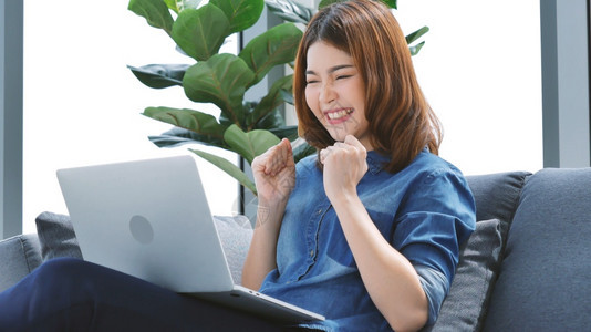 成功在家工作参加庭办公室膝上型电脑在线会议的妇女使用笔记本的企业家女商妇坐在沙发技术上新的正常生活方式快乐女人打键盘手提电脑微笑图片
