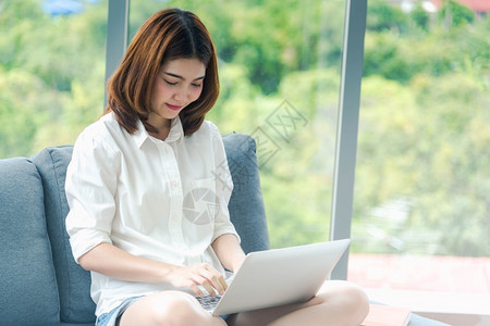 公司的消息学生在家工作参加庭办公室膝上型电脑在线会议的妇女使用笔记本的企业家女商妇坐在沙发技术上新的正常生活方式快乐女人打键盘手图片