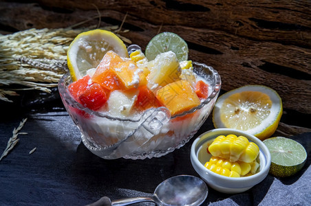 热带新鲜水果沙拉玻璃碗里放着牛奶和燕麦片配上深色背景的玉米甜味健康早餐素食选择焦点纤维糖浆成熟图片