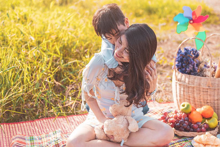 夏天亚洲人小裔男孩骑着超强的妈在草地上野餐时在母亲和儿子一起玩母亲节庆祝并欣赏夏季人与生活方式这个概念的主题图片