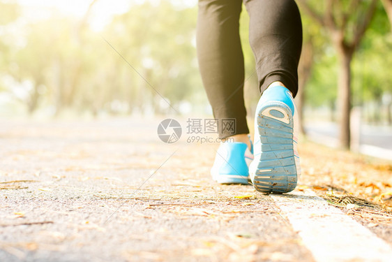 跑步健身女的腿正跑在街上公园里周围都是大自然早晨阳光照耀右脚聚焦着她的锻炼冥想图片