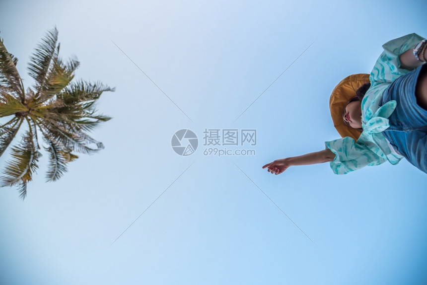 低角度观察感女短牛仔裤中空跳跃跨过摄像头在海滩下拍摄有椰子和空中高架概念旅行积极生活方式克服障碍等在海滩上跳跃或跨越一步勇敢的飞图片