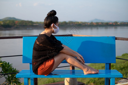 坐在长凳上戴口罩防护的女青年图片