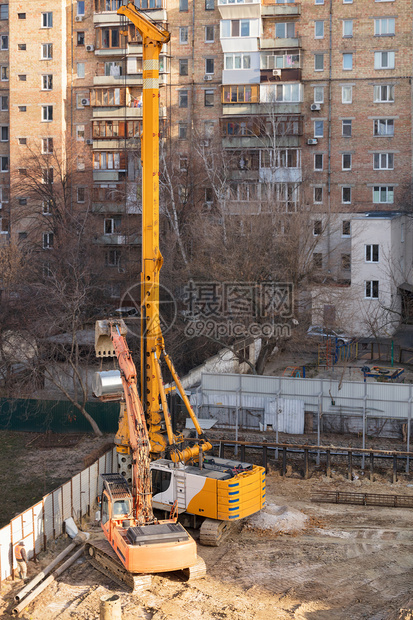 地点重型建筑设备挖土机和高功力起重钻井洞用于在为未来房屋打地基铺设混凝土堆积石的地面上埋设高强度起重器钻孔一个垂直图象复制空间一图片