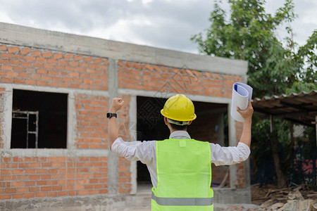 服装安全建筑人看着工地举起手来表达他欢乐的心情一建造人看筑工地举起手来表达他的欢乐时光实业家图片