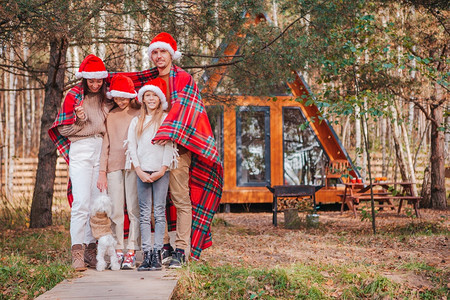 快乐的家庭四口在圣诞帽子的幸福家庭享受圣诞假期父母和孩子在毯裹着的孩美丽家庭孩子们在圣诞节散步狗包裹一种图片