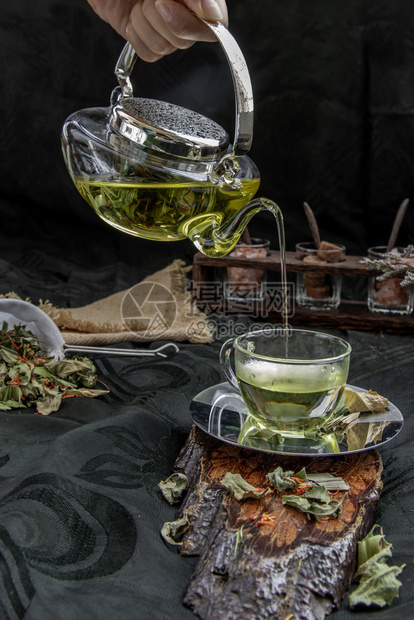 一种自然草本热板菜叶茶配有印度沼泽跳蚤班植物叶和红绿花干盐色的黄叶由玻璃茶壶倒入一杯子含茶药草和叶休假图片