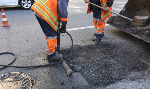 a道路维修服务人员大队清除旧沥青在道路建设中用1个打火机和铲子把旧沥青搬进挖土车推工兵夸克大队在道路建设中用铲子清理部分沥青男人图片