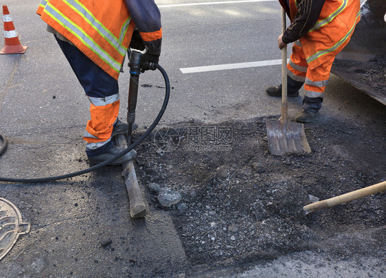 a道路维修服务人员大队清除旧沥青在道路建设中用1个打火机和铲子把旧沥青搬进挖土车推工兵夸克大队在道路建设中用铲子清理部分沥青建造图片