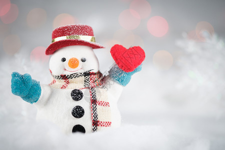 Bokoh背景的雪人和小型心脏枕头有圣诞快乐或新年季节喜好AF点选择经典铬音等复制空间语气为了红色的图片