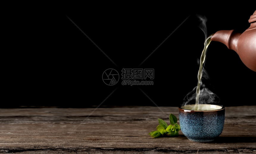 绿色为了菜单热茶从壶倒到蓝碗里古老的木板桌蒸汽在杯子上方茶叶贴在杯子旁边喝完茶礼最低限量主义复制文本空间图片