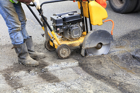 街道路施工消除技术员在修理公路时启动汽油钻石发机以清除旧沥青工人开始使用汽油切割机的发动以便切断和清除公路上的坏沥青b修车图片
