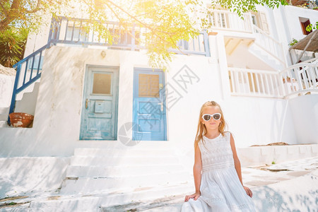 风景在希腊Mykonos岛的典型希腊传统村庄街上白色墙壁与多彩门希腊Mykonos岛的小可爱女孩在旧街道上露着外装的小可爱女孩M图片