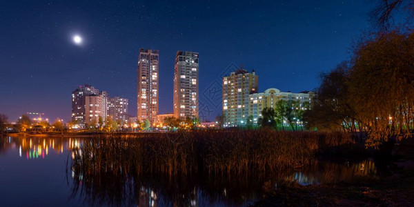 夜晚小时乌克兰基辅波隆区现代建筑的夜景从纳塔卡公园南部看月亮照在星蓝天空中灯光反射到德尼佩尔河上家图片