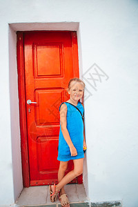 Mykonos女孩度假户外离红希腊传统门近处的Mykonos女孩在典型希腊传统村老街上可爱的小姑娘夏天米科诺斯地中海图片