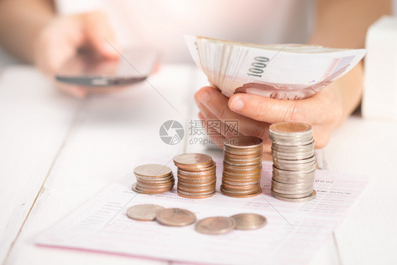 硬币账单使用手机在办公桌上的女商人选择焦点在光线下人类图片