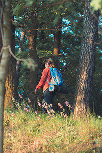 国民背包旅行泡沫在暑假期间带着背包走在穿过森林的道路上走过森林的青年妇女徒步旅行者图片