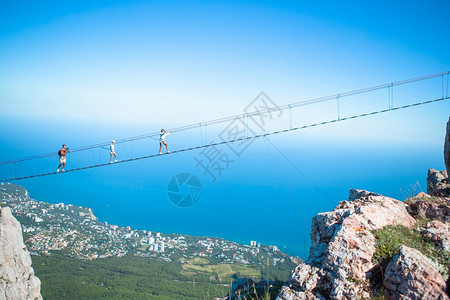 风景优美游客在海山背景下勇敢的父亲和孩子家庭在悬吊桥上家庭渡过绳桥上的裂缝黑海背景克里米亚俄罗斯克里米亚自然图片