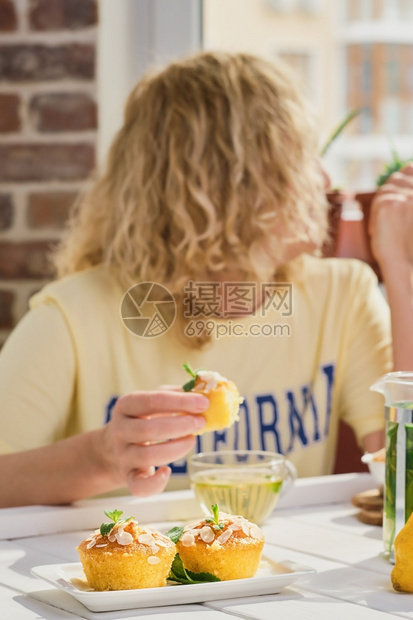 生日Lemon松饼关闭选择焦点在咖啡中早餐的年轻女士看着窗外拿柠檬纸杯蛋糕在他的手桌子被阳光照亮了早餐的想法周末保持茶图片