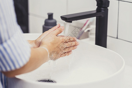 治疗亚洲妇女在家里浴室用水龙头洗手Covid19大流行的保健清洁和无照护概念等近身情况社会的福利图片