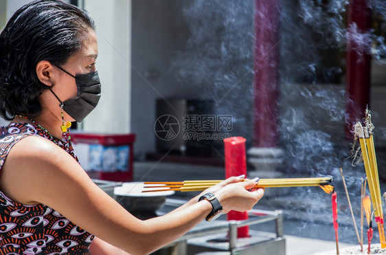 棍子关心预防戴着医用口罩以防感染的亚洲妇女正在寺庙里烧香口罩以保护自己免受冠状的侵害在城市被看到选择焦点图片