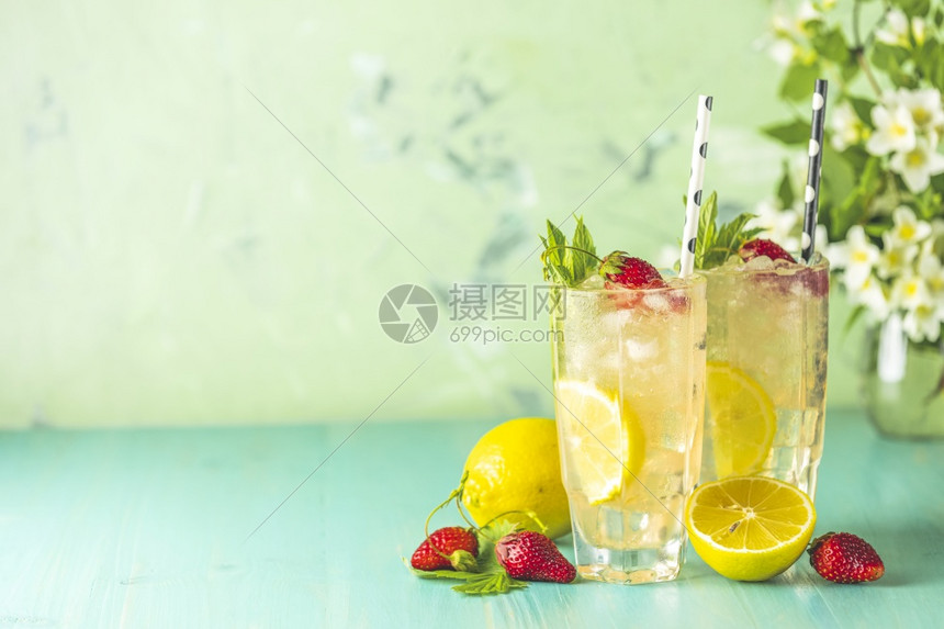 酒精茶点玛格丽塔两杯冰冷的清饮料柠檬和草莓两杯加柠檬和草莓配有酒吧工具放在绿色木制桌上白花朵新鲜鸡尾酒及冰果和草药装饰品图片