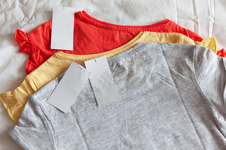三件新的短色T恤衫有白背景的清洁标签概念购物夏季销售折扣有机棉花服装再利用衣物编织珊瑚有机的图片