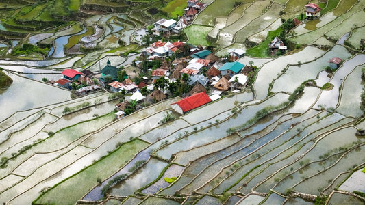 景观旅行日出在米田边附近的村庄房屋惊人的抽象纹理天空在菲律宾伊富果省巴瑙埃水中闪烁多彩的反光图片