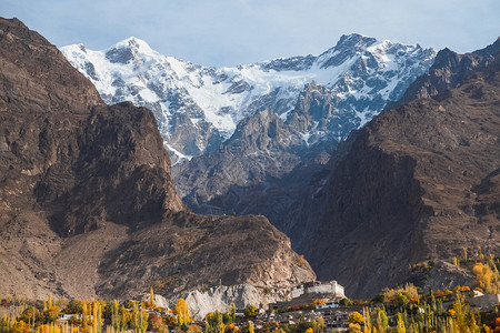 巴基斯坦GilgitBaltistan的KarimababHunza山谷秋天与古老的Baltit堡和树叶一起在卡拉科姆山脉上雪盖背景图片