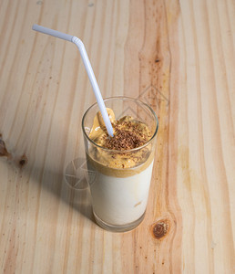 泡沫在木制的纸质桌面板上自制Dalgona咖啡杯装在木制拖鞋板上用鲜奶冲来即时咖啡使韩国美味饮品Trendy饮料与巧克力屑和白稻图片