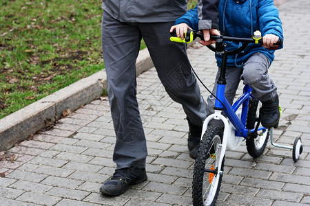 男孩体育娱乐一个男人在自行车旁边走骑自车去给孩子看父亲教儿骑脚踏车公园女孩外貌图片
