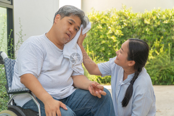 那里中年人和肥胖瘫痪嘴唇手被钉住的和轮椅上利姆软弱有一个妻子用毛巾遮住丈夫的脸充满爱和希望皱巴的四肢图片