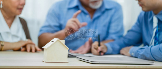 保险代理经与亚洲夫妇祖父母在交易成功后与笔记本电脑签订横幅房屋模型财务规划师完成房地产销售老年团结室内的图片