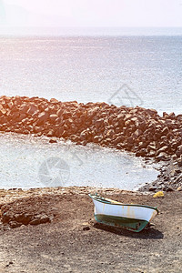 特内里费岛诺角附近的海洋岩石岸和孤独的小船火山岩与明亮的蓝色海浪加那利群岛的晴天特内里费岛诺角附近的海洋岩石岸和孤独的船火山岩与图片