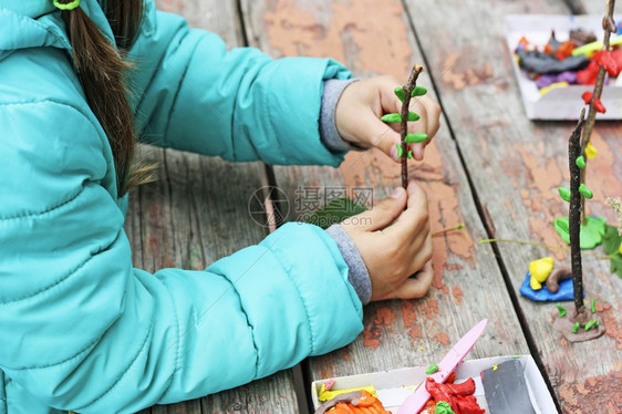 儿童用粘土和各种形状的天然材料玩耍女孩雕塑在散步时用胶弹打人在街头漫步时女孩会以泥和各种形状的自然材料玩弄塑制品新的木头力量图片