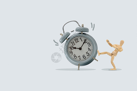 计时器Wooden假人踢一个大钟孤立于蓝色背景想法和时间图片概念死的重图片