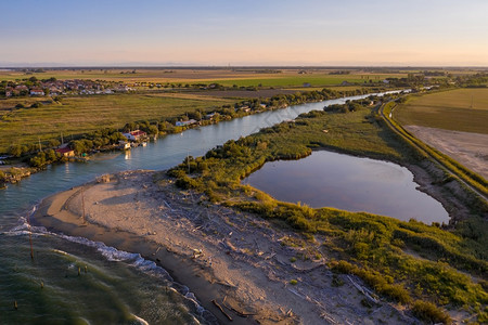 在RavennaFiumiUniti附近山谷的美丽景观中河水与典型的渔民在日落时开小屋流入大海风景优美单位海岸图片