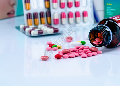 药店铁红色的片剂药丸从琥珀色玻璃药瓶中散开在泡罩包装中的模糊胶囊上红色和粉药片物使用概念止痛药制业产品图片