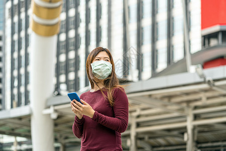 医疗的亚洲妇女手持智能机使用带安全医疗面罩的智能移动电话以防止Corona或Covid19在前往市中心商业保健和感染概念工作时爆图片