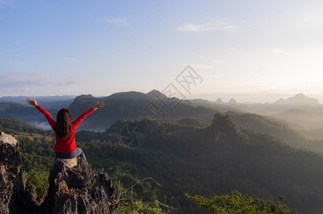 徒步旅行者女一位年轻子在明日上山他很高兴成功攀登了山峰欣赏大自然晨雾和美丽的太阳光登山岩爬到泰国梅洪子市BanJaboMeeHo图片