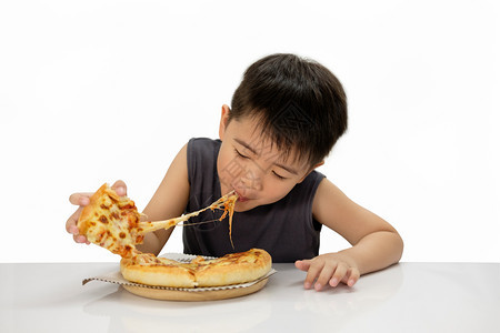 亚洲男孩乐于吃披萨与热干酪正在融化伸展木板上白背景孤立选择fucus点拉伸嘴好吃图片