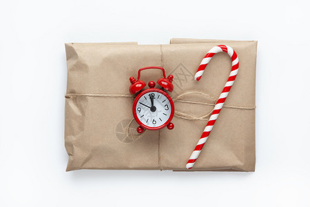 圣诞节最小以棕色手纸包成的圣诞礼物与灾祸捆绑在一起用甘蔗糖和小模拟钟装饰在白色背景上最起码的风格最佳观庆祝生态概念天图片