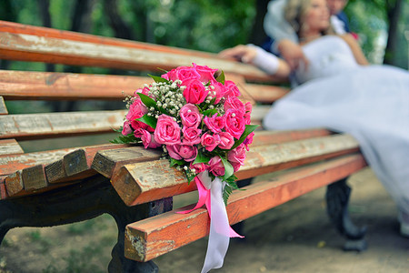 新婚夫妇花束在木凳上新娘和郎在背景中重点放在鲜花背景上漂亮的幸福婚姻图片