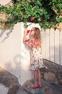穿着白裙子的希腊女孩在Mykonos街上享受户外游乐在Mykonos岛有白色墙壁和多彩大门的典型希腊传统村庄街上的老希腊传统村落图片