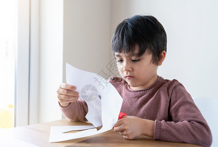 学龄前儿童保持孩子在家学习如何剪纸儿童在家里享受艺术和手工活动在Cavd19关闭期间家庭敲打或玩耍和学习Kid学习如何剪纸孩子呆图片