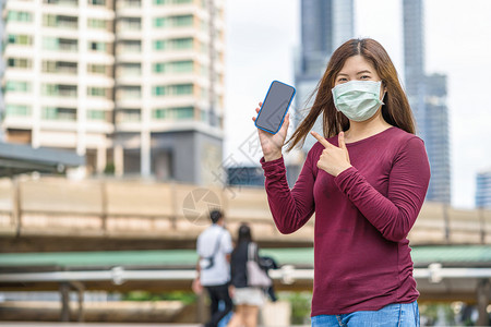 户外戴口罩手拿手机的女性图片