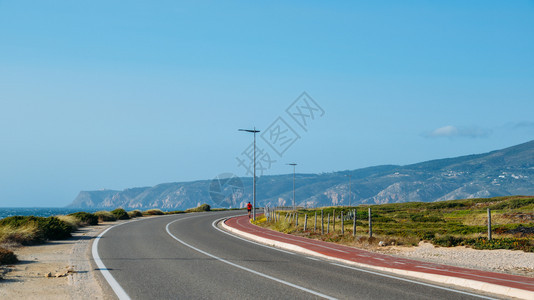途径天空孤独的无法辨认步行者或跑在PraiadoGuincho的人行道上前往葡萄牙辛特拉附近的CabodaRoca海图片