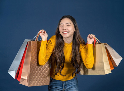 奢华女带着一个以经典蓝肤色背景令人兴奋的购物袋销售折扣黑色星期五和消费主义概念夏季时装丰体等令人兴奋的东西笑着亚洲快乐的年轻微笑图片